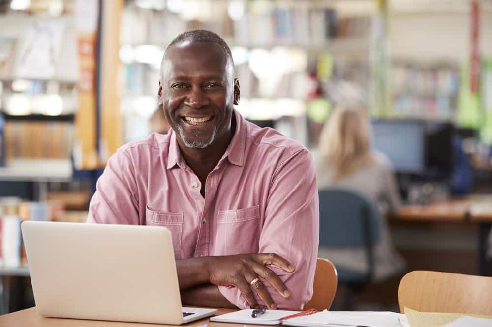 man smiling in cafe using computer